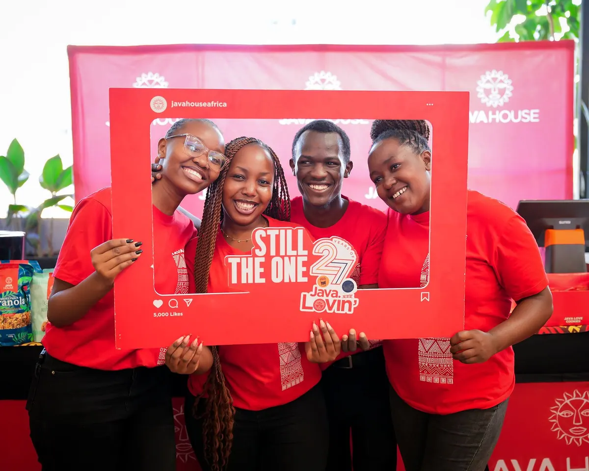 Four Java House staff in red T-shirts posing with a photo frame prop