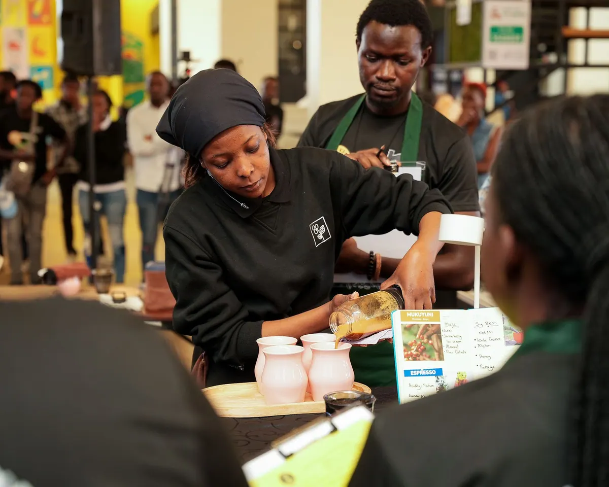 A competitor preparing drinks at her station while judges watch