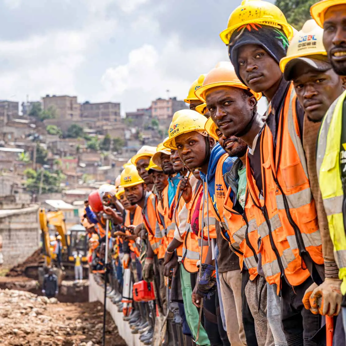 Construction workers in hard hats and hi-vis vests lined up on site