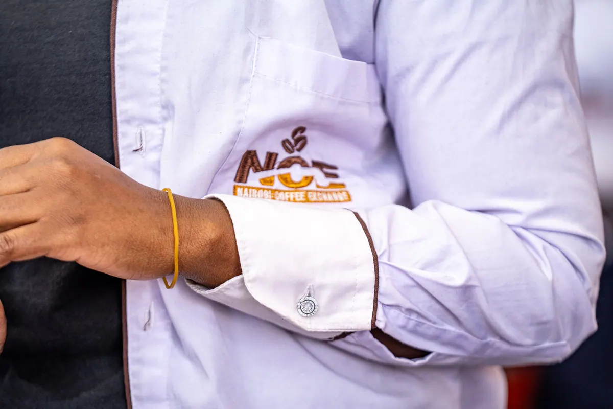 The NCE logo embroidered on a white coat cuff