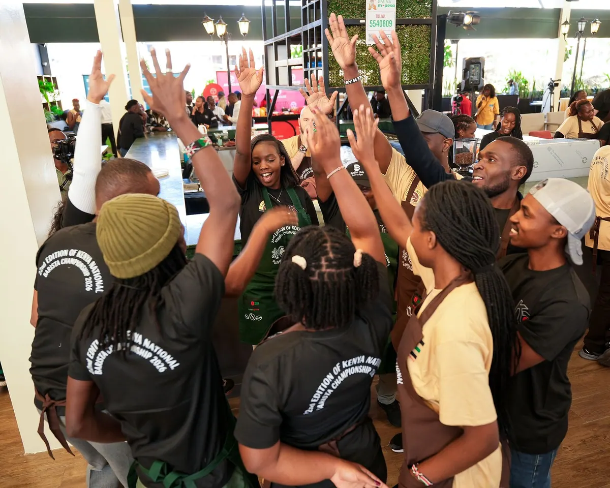 Baristas in aprons cheering with their hands in the air