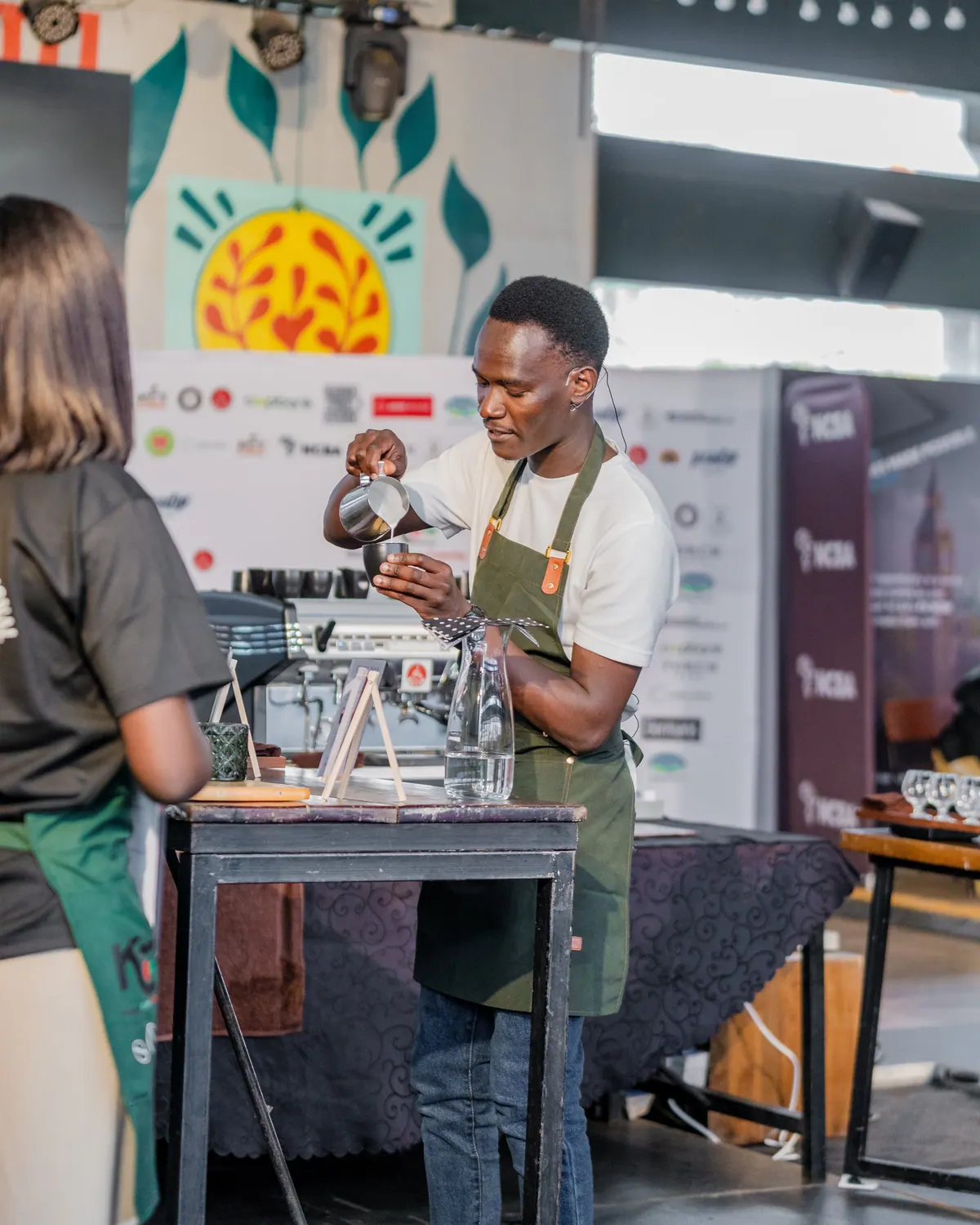 A barista in a green apron at his station