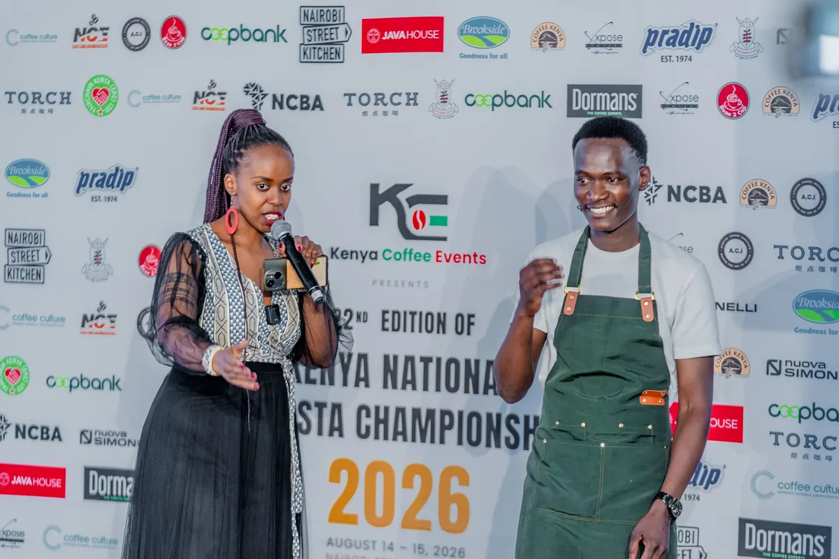 The host and a competitor on stage in front of the championship sponsor wall