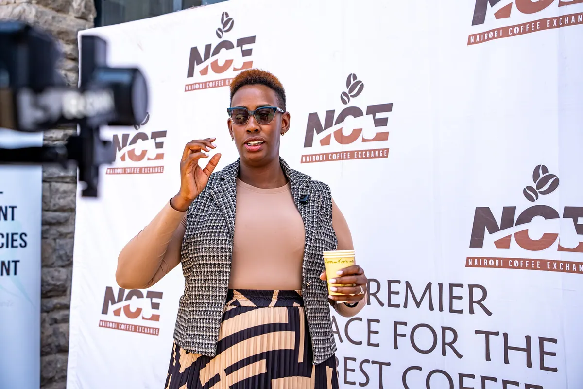 A Nairobi Coffee Exchange speaker in front of the NCE backdrop