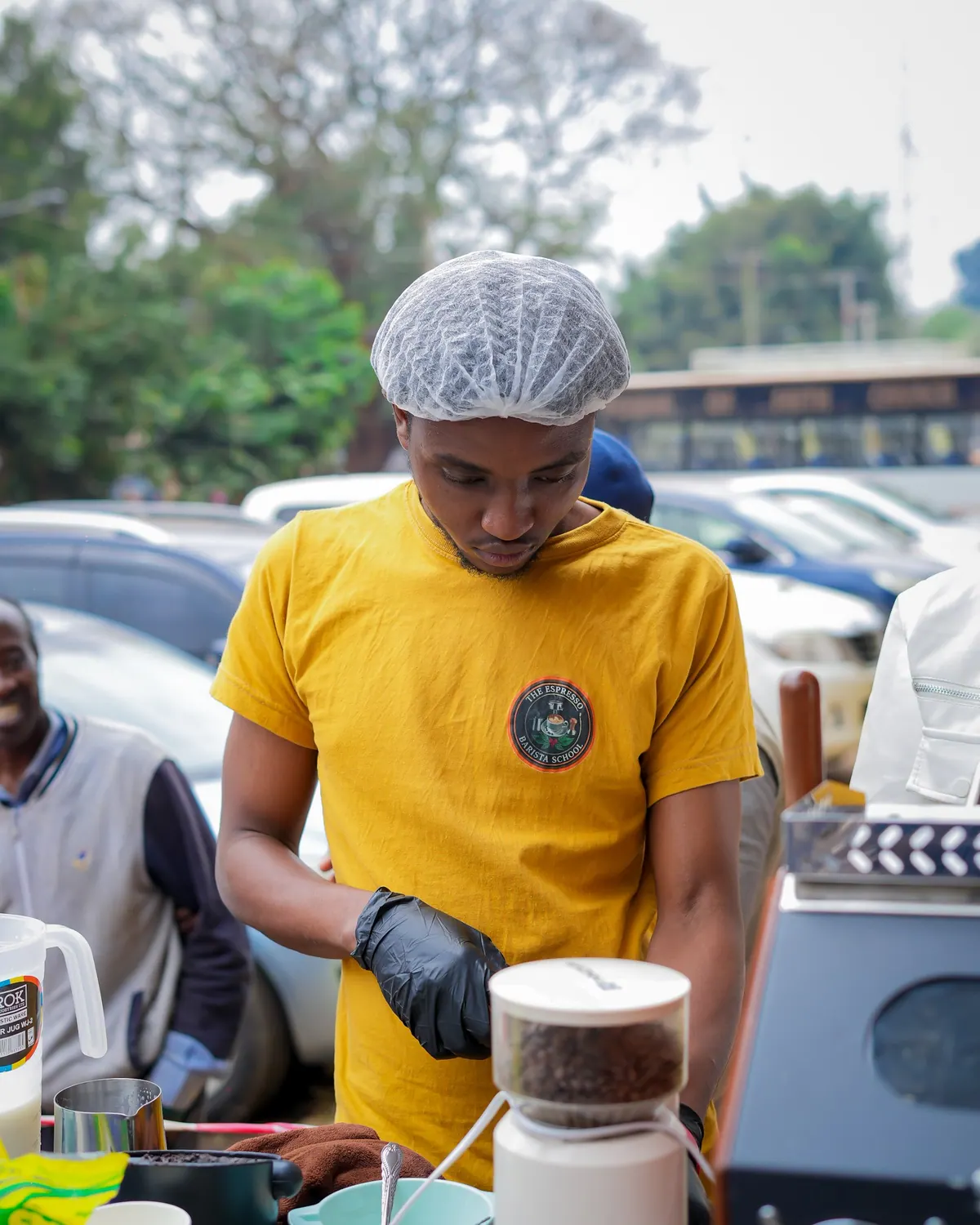 A barista in a yellow T-shirt preparing coffee outdoors