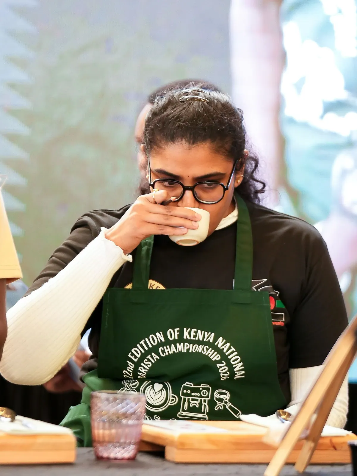 A judge in a championship apron tasting from a cup