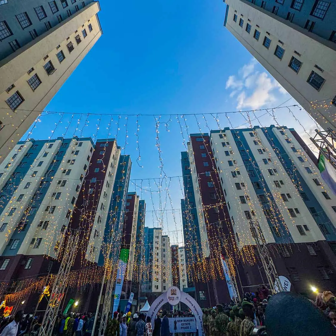 Apartment towers strung with lights, seen from below